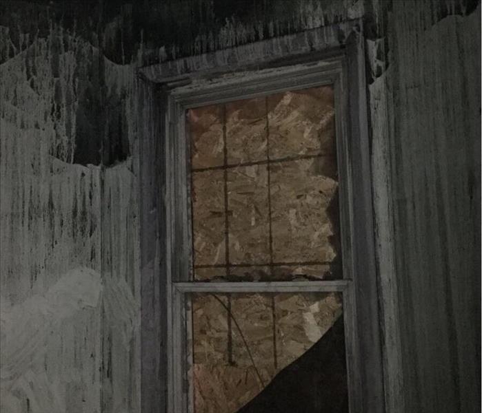 Soot covered room with a boarded up window.