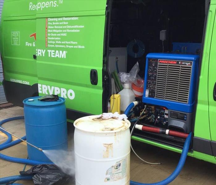 SERVPRO van with a white and blue barrel in front and blue hoses on the ground.