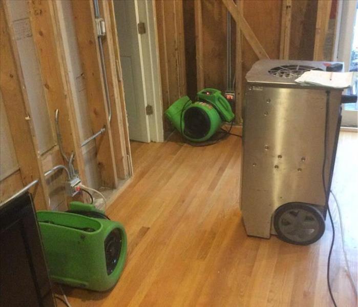 2 green air movers and a silver dehumidifier on a hardwood floor.