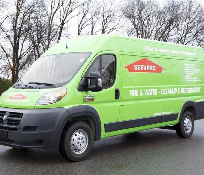 Green SERVPRO van with trees in the background.