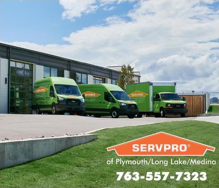 Three green SERVPRO trucks outside the office warehouse.