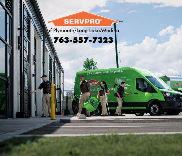 Green SERVPRO truck and employees outside of a building.
